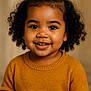 toddler, child, smiling, curly_hair, ponytail, sweater, mustard, knitwear, portrait, face, happy, cute, indoors, warm_colors, cozy, young_child, closeup, person, headshot, studio