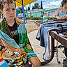 Maxwell joined the competition — help win amazing prizes! child, children, portrait, outdoor, playground, picnic_table, sunshade, yellow_canopy, cartoon_blanket, towel, drinks, bottles, wet_hair, seated, serious_expression, summer, neighborhood, fence, trees, sky