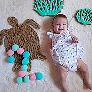 Adria participe au concours pour gagner de l'argent avec cette photo : baby, infant, child, smiling, white_clothing, romper, woven_mat, turtle_shape, pom_poms, number_two, decorative_coral, teal_color, fluffy_surface, indoor, playful, cute, happy, face, legs, arms