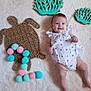 baby, infant, child, smiling, white_clothing, romper, woven_mat, turtle_shape, pom_poms, number_two, decorative_coral, teal_color, fluffy_surface, indoor, playful, cute, happy, face, legs, arms
