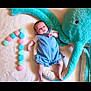 Adria a rejoint le concours — aidez-le/la à gagner de superbes lots ! baby, infant, blue_romper, plush_octopus, stuffed_animal, pom_poms, number_one, soft_surface, cute, child, toy, playful, milestone, celebration, lying_down, indoor, portrait, smiling, small_child, colorful