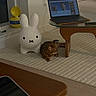 cat, bengal_cat, plush_toy, bunny, rug, coffee_table, laptop, remote_control, living_room, window, toy_story, container, striped_rug, floor, furniture, indoor, relaxed, electronics, screen, modern