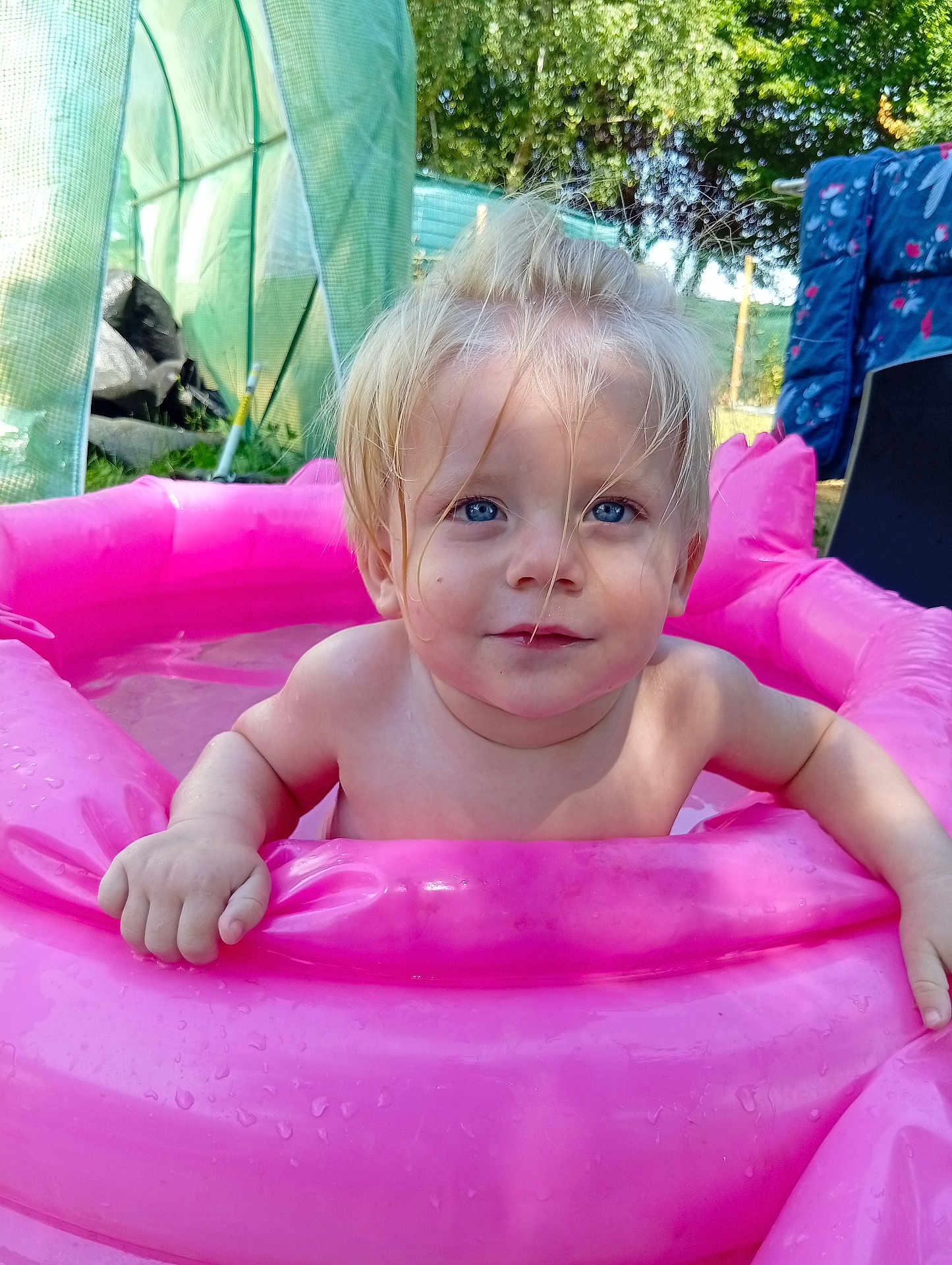 Djayan participe au concours pour gagner de l'argent avec cette photo : child, toddler, baby, inflatable_pool, pink, water, outdoor, summer, garden, greenery, blond_hair, blue_eyes, wet_hair, playing, fun, sunlight, daytime, cute, happy, portrait