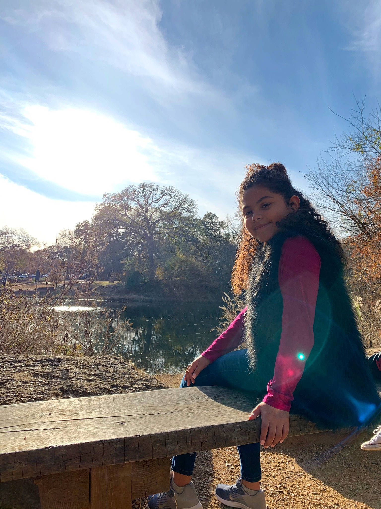 Nevaeh is registered to the contest to win money with this photo: blue, cloud, grass, jacket, jeans, leaf, mountain, outerwear, person, photography, pink, sitting, sky, smile, soil, spring, sunlight, textile, tree, winter