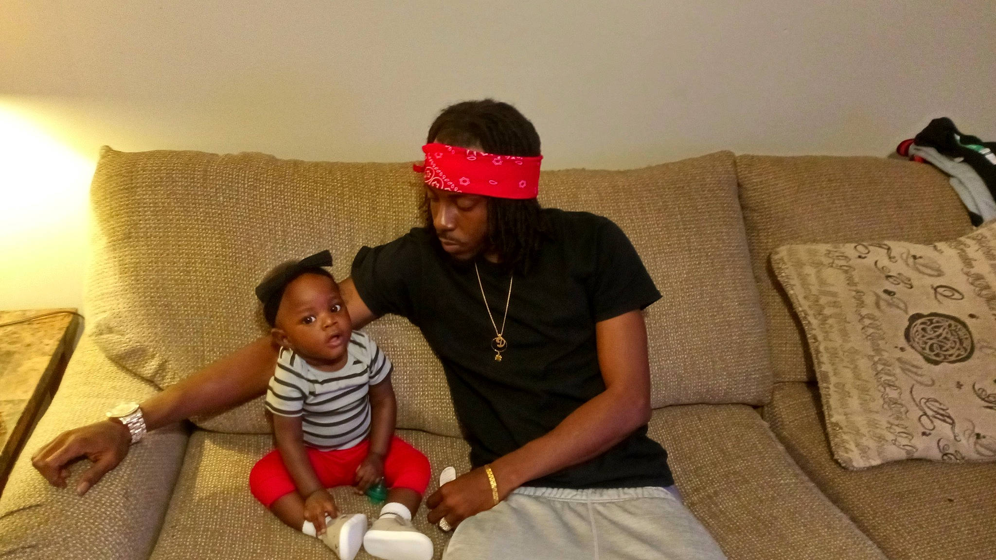 Samira is registered to the contest to win money with this photo: arm, cap, child, comfort, couch, elbow, event, flooring, fun, human_leg, jewellery, knee, lap, living_room, person, room, sitting, t_shirt, thigh, toddler