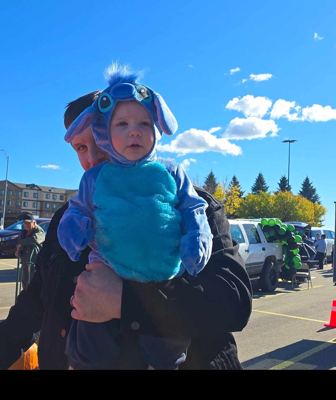 Edward joined the competition — help win amazing prizes! toddler, child, costume, blue, outdoor, sunny, sky, clouds, balloons, parking_lot, adult, person, holding, festival, event, trees, vehicle, black_jacket, cute, playful