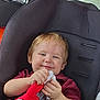 toddler, child, car_seat, stuffed_toy, toy, smiling, happy, seatbelt, car_interior, seat, clothing, red, black, window, headrest, person, young_child, cute, indoors, baby