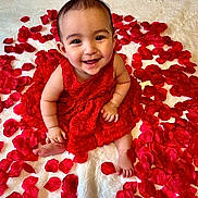 Aeris joined the competition — help win amazing prizes! adorable, baby, blanket, bright, celebration, child, closeup, cute, feet, flower_petals, hands, happy, indoors, infant, portrait, red_dress, rose_petals, sitting, skin, smiling