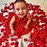 adorable, baby, blanket, bright, celebration, child, closeup, cute, feet, flower_petals, hands, happy, indoors, infant, portrait, red_dress, rose_petals, sitting, skin, smiling