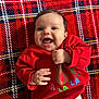 Emily is registered to the contest to win money with this photo: baby, cheerful, child, clothing, cozy, cute, face, festive, hands, happy, holiday, indoors, infant, lying_down, plaid_blanket, portrait, red_sweater, reindeer, smiling, young