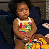 Angel is registered to the contest to win money with this photo: toddler, child, afro_hair, colorful_clothing, bracelet, toys, bed, blanket, indoor, portrait, cute, person, sitting, curious, furniture, playtime, bright_colors, soft_lighting, home, baby