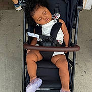 Angel joined the competition — help win amazing prizes! toddler, child, sleeping, stroller, curly_hair, white_outfit, floral_pattern, purple_shoes, footwear, seatbelt, outdoor, concrete, person, baby, nap, relaxed, black_stroller, casual, daytime, rest