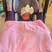 Athena is registered to the contest to win money with this photo: newborn, baby, infant, sleeping, car_seat, blanket, pink, bow, hat, portrait, face, closed_eyes, indoors, home, floor, furniture, cozy, resting, child, photography