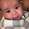 Carlyle Leonardo joined the competition — help win amazing prizes! adult_arm, baby, baby_clothing, blanket, bundled, child, close_up, cream, curious, cute, eyes, face, gray, indoor, infant, photograph, portrait, smile, soft_lighting, swaddled