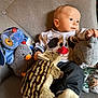 baby, child, plush_toy, stuffed_animal, dog_sweater, sitting, chair, indoor, cute, soft_toy, infant, portrait, clothing, couch, face, looking_away, hand, footwear, cozy, comfort