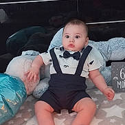 Kamil participe au concours pour gagner de l'argent avec cette photo : baby, infant, birthday_cake, candle, clothing, bow_tie, suspenders, blanket, star_pattern, plush_toy, floor, home_interior, television, decor, plate, celebration, child, sitting, cute, indoor