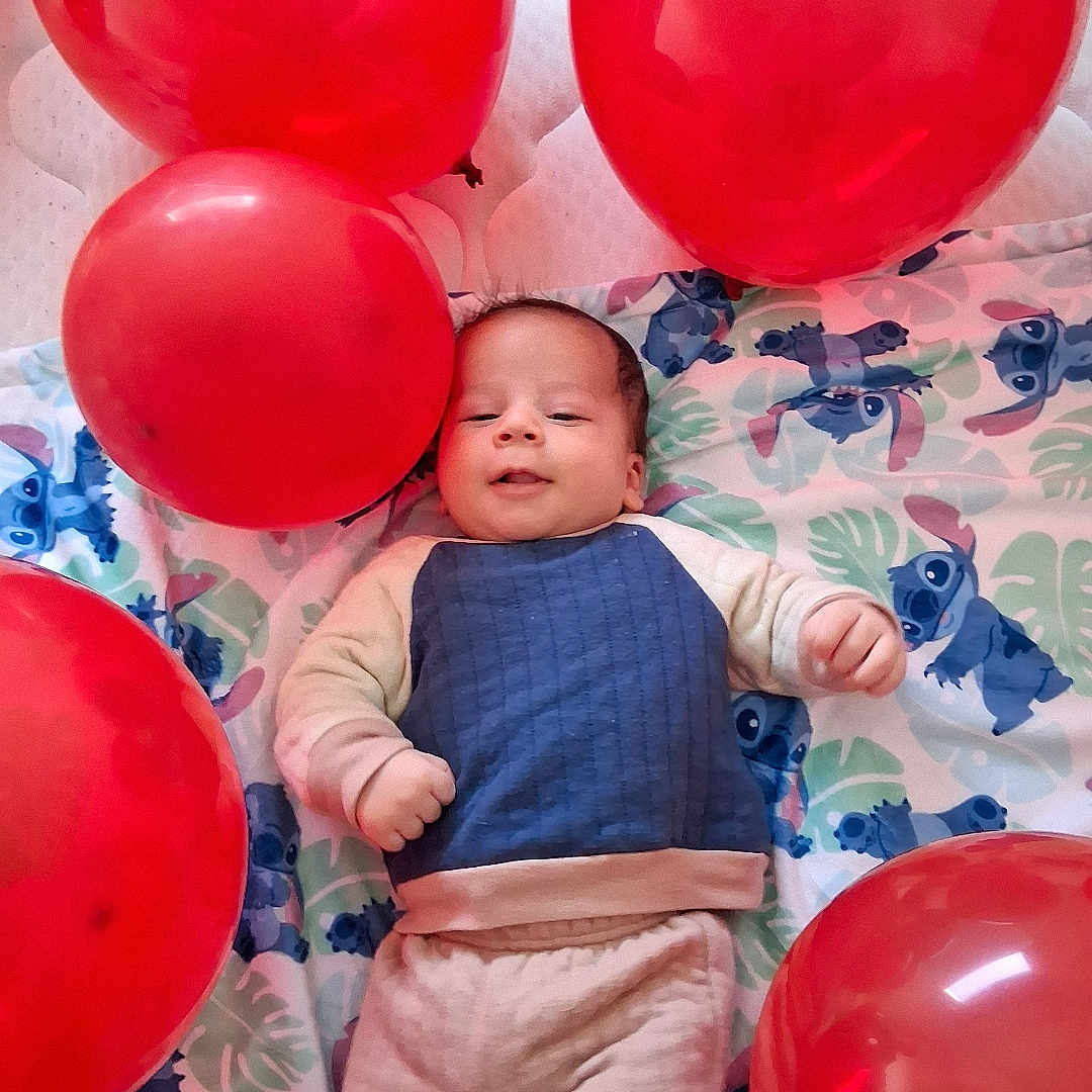 Massine joined the competition — help win amazing prizes! baby, balloon, blanket, blue_clothing, carpet, child, cute, face, floor, indoors, infant, laying_down, light, mattress, one_person, pale_skin, red_balloon, smiling, socks, toddler