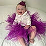 Aurore a rejoint le concours — aidez-le/la à gagner de superbes lots ! baby, child, clothing, cushion, cute, fabric, face, hand, happy, headband, indoors, infant, legs, person, portrait, purple, sitting, smile, tutu, white_background