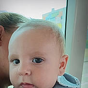 Lewis a rejoint le concours — aidez-le/la à gagner de superbes lots ! baby, child, face, portrait, close_up, curious, eyes, adult, holding, indoor, window, soft_light, expression, skin, head, clothing, bib, person, young, human