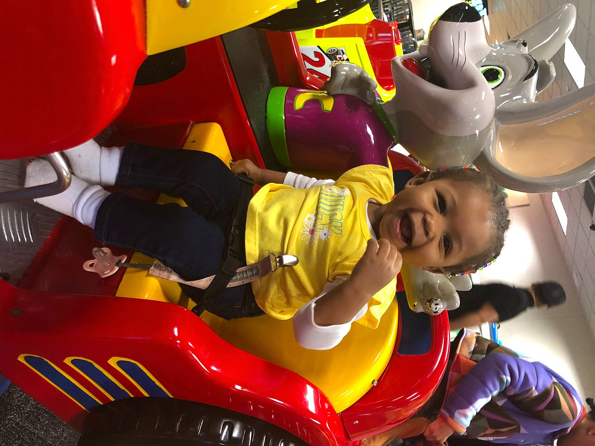 Armani is registered to the contest to win money with this photo: amusement_ride, automotive_design, automotive_exterior, automotive_tire, balloon, child, event, fun, green, leisure, light, motor_vehicle, person, personal_protective_equipment, recreation, red, smile, snapshot, toddler, white