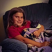 Luna is registered to the contest to win money with this photo: child, girl, kitten, cat, blanket, armchair, smile, indoors, cozy, cuddling, comfort, furniture, young, pet, happy, casual_clothing, relaxing, home, portrait, warm_lighting