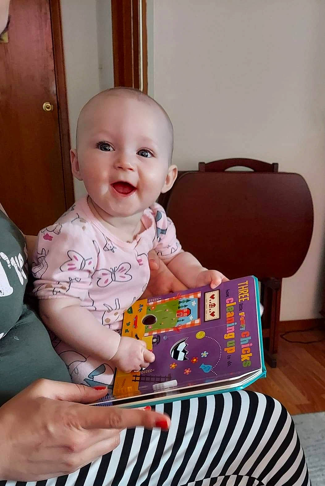 Holland is registered to the contest to win money with this photo: baby, baby_playing_with_toys, baby_toddler_clothing, child, door, event, face, flooring, fun, happy, office_equipment, person, pink, play, product, sharing, sitting, sleeve, smile, t_shirt