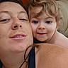 Emmett is registered to the contest to win money with this photo: adult, bedroom, blonde_hair, blue_eyes, child, close_up, cuddling, curly_hair, face, family, indoors, mother, necklace, pillow, portrait, selfie, shoulder, smiling, toddler, wooden_headboard