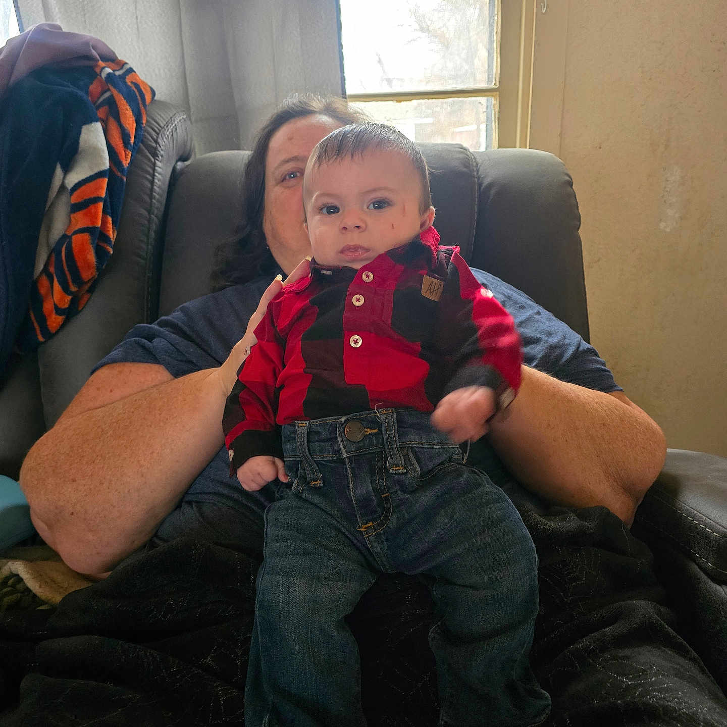 Emmett is registered to the contest to win money with this photo: adult, baby, blanket, casual, chair, child, clothing, curtains, face, hand, home, indoor, jeans, person, plaid, portrait, relaxed, shirt, sitting, window