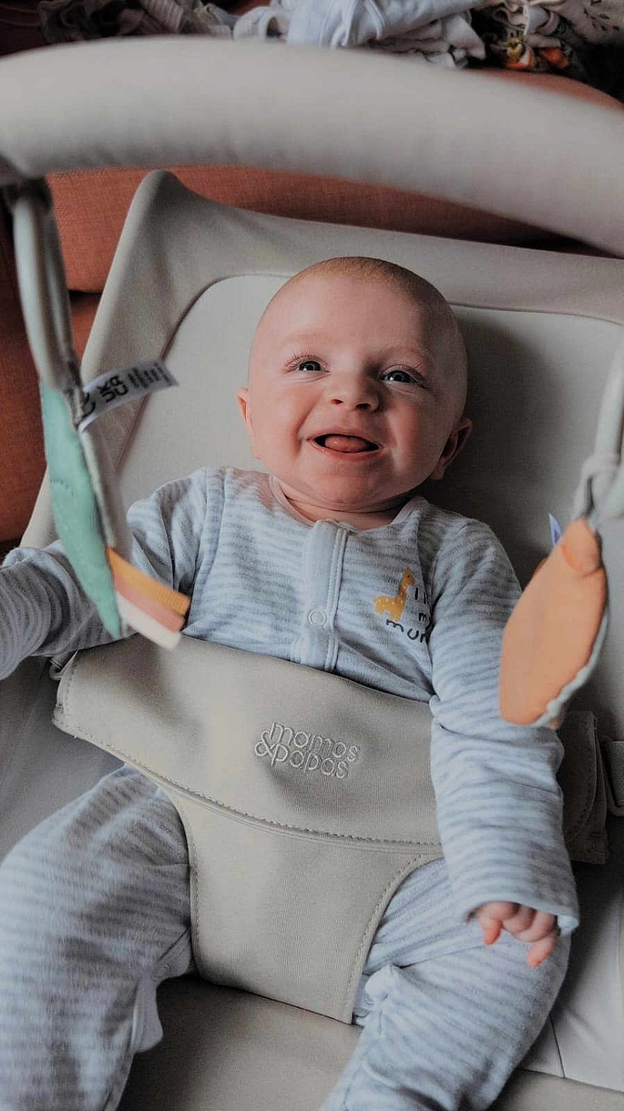 Patrick is registered to the contest to win money with this photo: baby, smiling, infant, onesie, baby_seat, toy, hanging_toy, giraffe_design, happy, cute, child, indoor, soft_light, closeup, face, person, seatbelt, comfort, young_child, playful