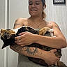 Nala joined the competition — help win amazing prizes! person, cat, bathroom, door, towel, tattoo, sink, faucet, smile, holding, calico_cat, earbuds, wall_art, indoor, portrait, decor, hand, arm, light, mirror