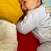 Inaya participe au concours pour gagner de l'argent avec cette photo : baby, smiling, lying_down, pillow, blanket, bed, colorful, happy, child, infant, face, clothing, soft_texture, cozy, cute, person, skin, head, ear, mouth
