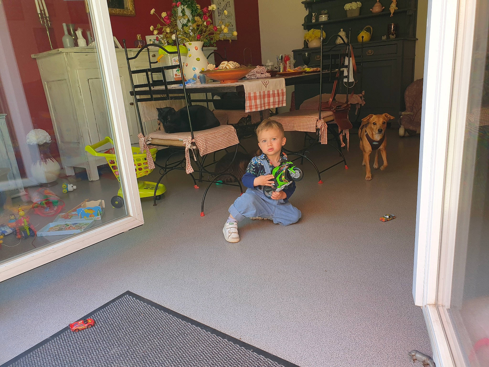 Izaak participe au concours pour gagner de l'argent avec cette photo : bookcase, chair, child, door, floor, flooring, fun, furniture, hardwood, home_door, house, houseplant, living_room, person, plant, room, shelf, table, toddler, toy