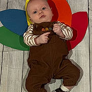 Cowen joined the competition — help win amazing prizes! baby, child, floor, wood_floor, overalls, striped_shirt, colorful_petals, paper, headwear, footwear, shoes, socks, lying_down, indoor, cute, portrait, person, infant, playful, background