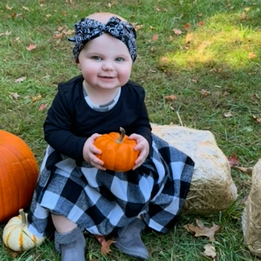 Mavis joined the competition — help win amazing prizes! baby, clothing, face, food, footwear, grass, head, outdoors, pants, person, photography, plant, portrait, produce, pumpkin, shoe, sitting, soil, squash, vegetable