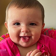 Leanna joined the competition — help win amazing prizes! baby, child, smiling, tongue_out, pink_clothing, face, hands, colorful, cushion, patterned, happy, closeup, indoor, infant, portrait, cute, joyful, young_child, expression, warm
