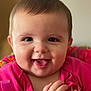 baby, child, smiling, tongue_out, pink_clothing, face, hands, colorful, cushion, patterned, happy, closeup, indoor, infant, portrait, cute, joyful, young_child, expression, warm