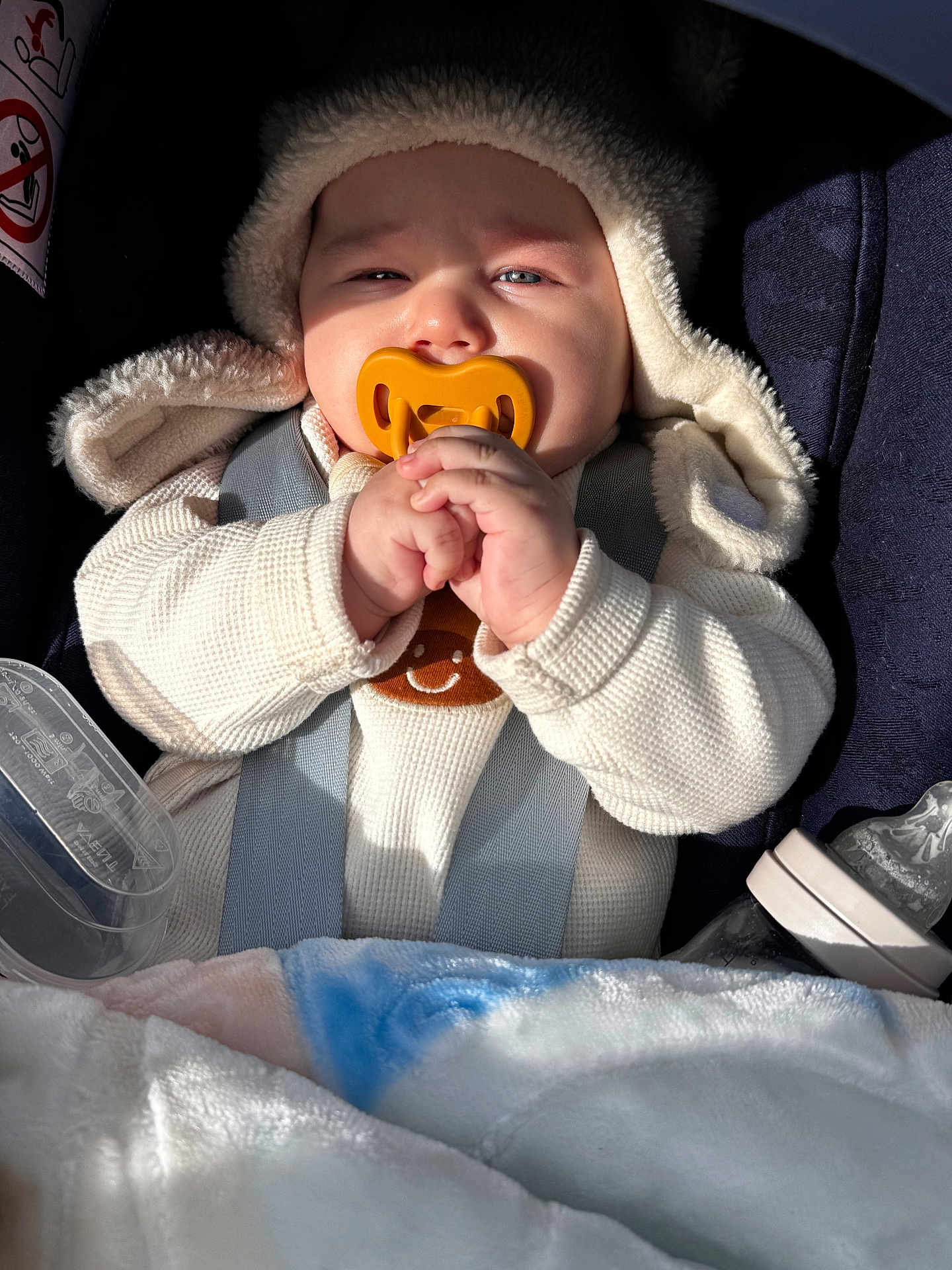 Ilyane a rejoint le concours — aidez-le/la à gagner de superbes lots ! baby, pacifier, hooded_sweater, car_seat, blanket, bottle, infant, clothing, hand, face, child, seatbelt, soft_toy, warm, cute, newborn, portrait, indoors, comfort, baby_care