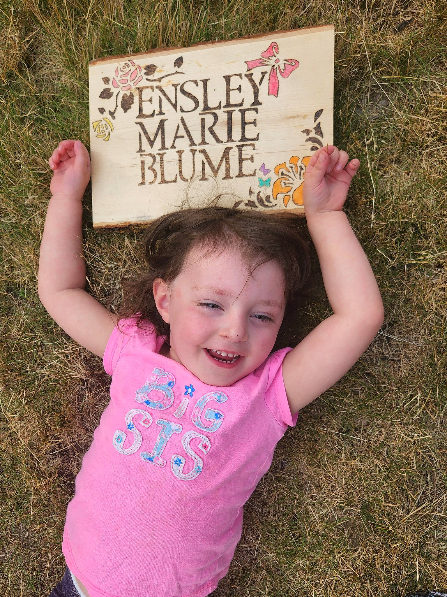Ensley is registered to the contest to win money with this photo: baby_toddler_clothing, cool, face, facial_expression, finger, font, fun, gesture, grass, hairstyle, handwriting, happy, joy, leaf, mammal, natural_environment, person, pink, product, sleeve