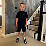 Jaxon is registered to the contest to win money with this photo: child, boy, indoor, stairs, carpet, wall, black_clothing, shorts, tshirt, sneakers, smile, standing, person, home, staircase, sock, casual, young, fashion, portrait