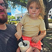 Serena joined the competition — help win amazing prizes! child, adult, outdoor, tree, sunlight, cup, spoon, food, messy_face, casual_clothing, person, beard, glasses, parking_lot, sidewalk, daytime, holding, pink_skirt, yellow_shirt, nature