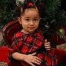 child, toddler, portrait, sitting, smiling, thumbs_up, red_dress, plaid, christmas, christmas_tree, holiday, chair, indoors, ornaments, festive, curly_hair, hair_bows, family_photo, studio_photography, wooden_furniture