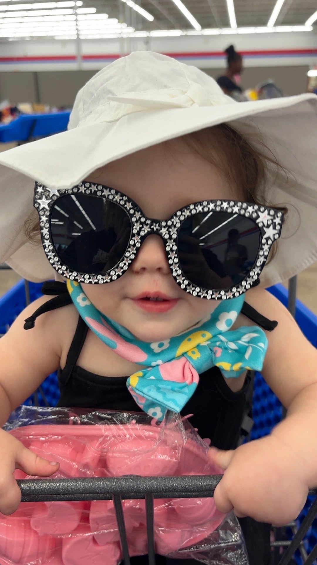 Janet joined the competition — help win amazing prizes! toddler, child, sunglasses, hat, shopping_cart, scarf, indoor, store, retail, person, fashion, accessories, cute, baby, holding, colorful, plastic, packaging, portrait, shopping