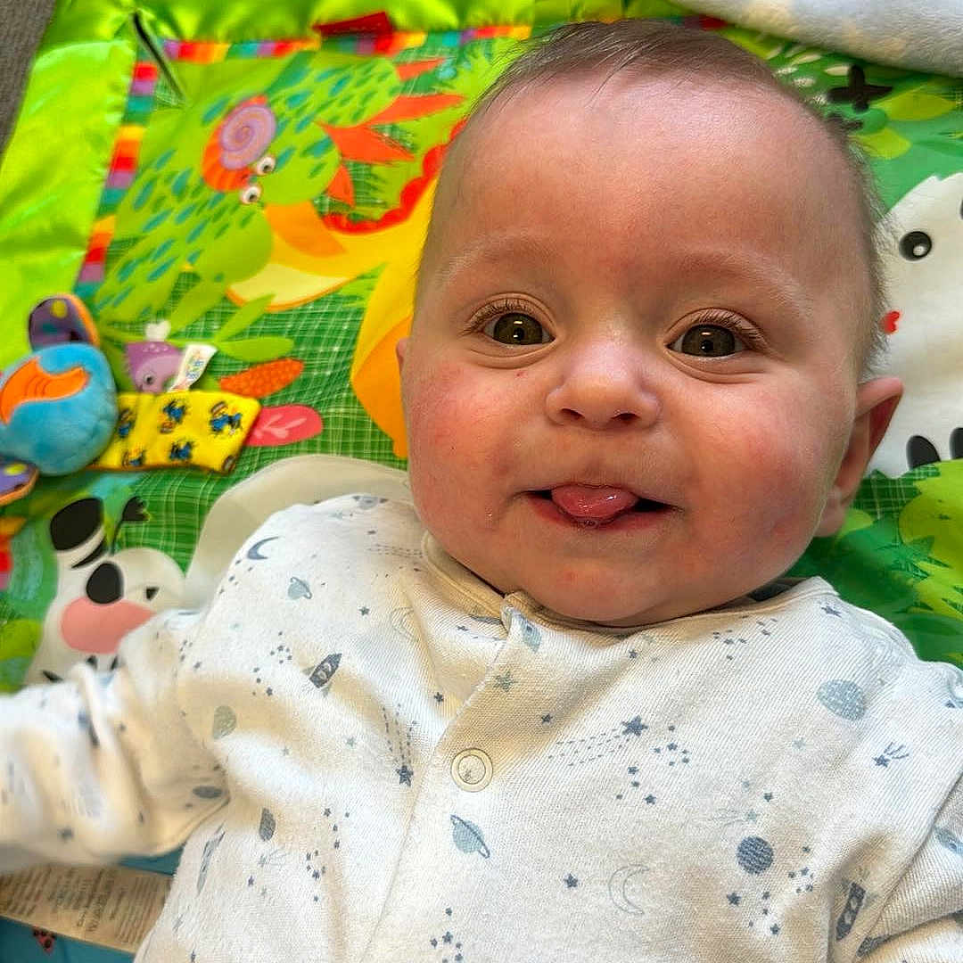 Noah is registered to the contest to win money with this photo: baby, bed, blanket, clothing, couch, cushion, face, furniture, happy, head, homedecor, laughing, linen, newborn, person, photography, pillow, portrait, quilt, smile