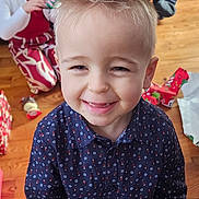 Esteban a rejoint le concours — aidez-le/la à gagner de superbes lots ! child, boy, smiling, happy, indoor, holiday, presents, gift_wrapping, floor, wooden_floor, shirt, patterned_clothing, blonde_hair, spiky_hair, girl, red_clothing, white_cardigan, family, celebration, portrait