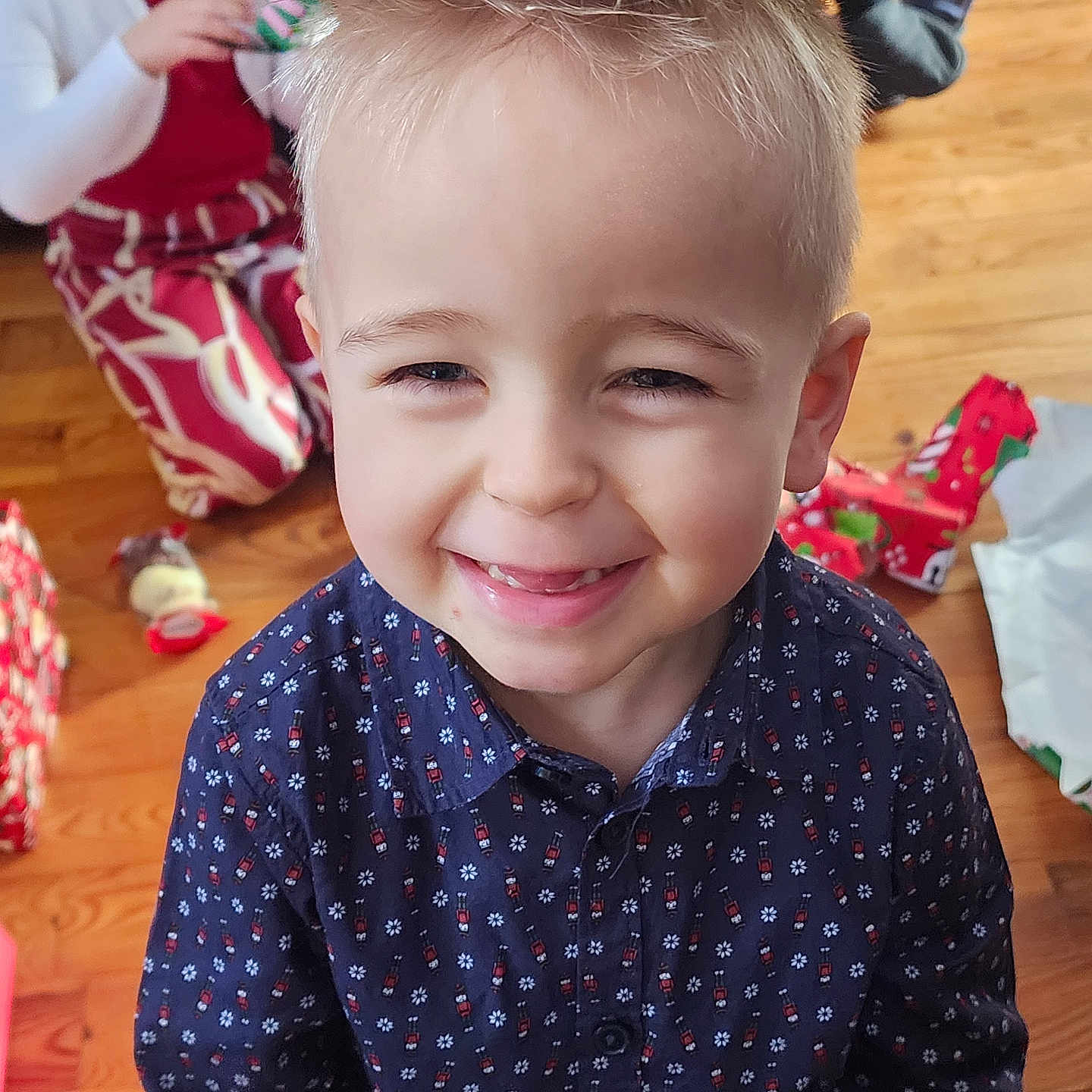 Esteban a rejoint le concours — aidez-le/la à gagner de superbes lots ! blonde_hair, boy, celebration, child, family, floor, gift_wrapping, girl, happy, holiday, indoor, patterned_clothing, portrait, presents, red_clothing, shirt, smiling, spiky_hair, white_cardigan, wooden_floor