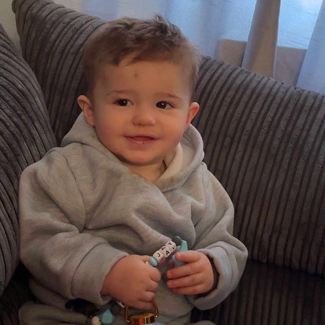 Elijah-Jay is registered to the contest to win money with this photo: baby, blanket, bodypart, clothing, couch, cushion, face, finger, furniture, hand, head, homedecor, knitwear, linen, pants, person, photography, portrait, sitting, sweater