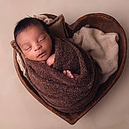 Jaïyden participe au concours pour gagner de l'argent avec cette photo : newborn, baby, sleeping, wrapped, blanket, brown, heart_shaped_bowl, wooden, soft_fabric, cozy, peaceful, portrait, infant, cute, toddler, child, skin, head, closed_eyes, indoor