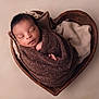 newborn, baby, sleeping, wrapped, blanket, brown, heart_shaped_bowl, wooden, soft_fabric, cozy, peaceful, portrait, infant, cute, toddler, child, skin, head, closed_eyes, indoor