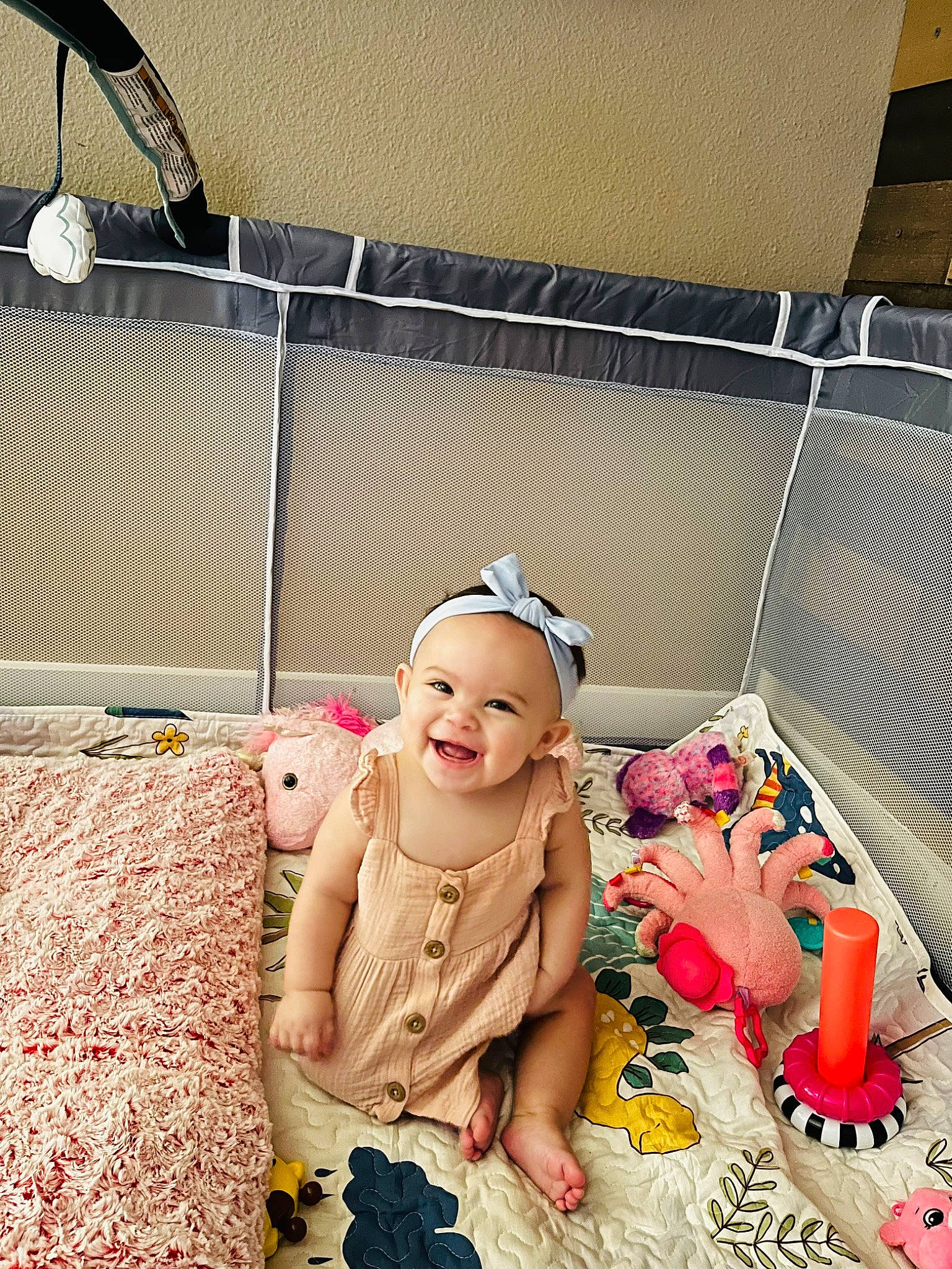 Isabel is registered to the contest to win money with this photo: abdomen, baby, baby_toddler_clothing, bag, child, comfort, event, fashion_accessory, flooring, fun, happy, joy, leisure, linens, pattern, peach, person, pink, play, room
