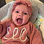 Elle is registered to the contest to win money with this photo: baby, child, smiling, pink_sweater, headband, knitted_clothing, cushion, indoor, checkered_floor, happy, person, seated, cute, face, expression, infant, apparel, portrait, small_child, clothing